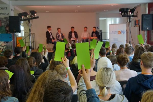 Jugendliche stimmen mit grünen Kärtchen über etwas ab