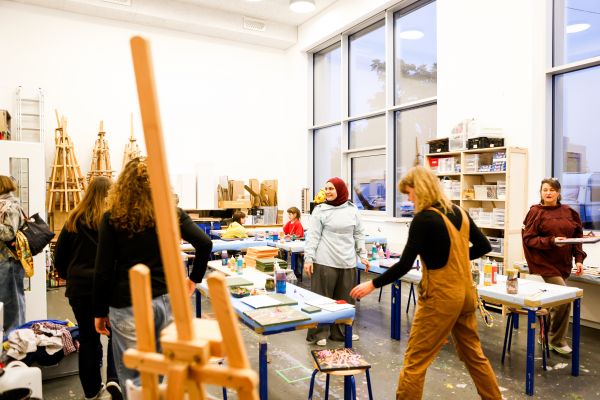 Ein Atelier. Im Vordergrund eine Staffelei, dahinter im Raum, Jugendliche und Kursleitung die Actionpainting machen.