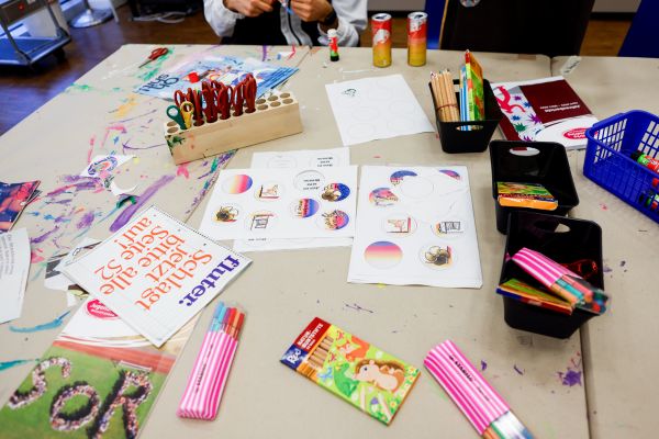 Bastelmaterial und Buttonvorlagen liegen verstreut auf einem Tisch.