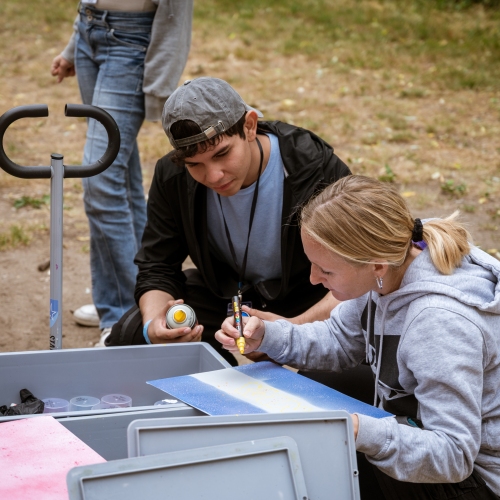 Zwei Jugendliche besprechen über einen Handwagen mit Spraydosen gebeugt ein Bild oder Design