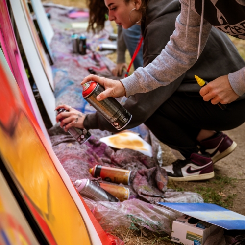 Viele Jugendliche mit Spraydosen sprayen gerade Graffiti auf große Platten