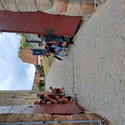 Ein offenes Burgtor. Jugendliche stehen links und rechts hinter den Türen und grinsen in Richtung der Kamera.