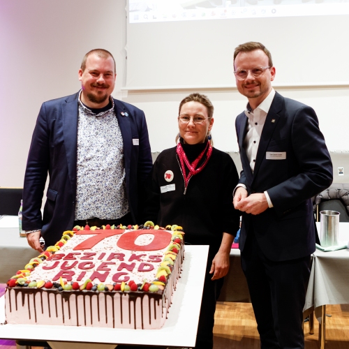 Drei Vorstände stehen hinter der Jubiläumstorte