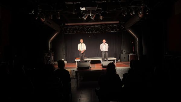 Zwei Personen in weißen Hemden auf einer Bühne