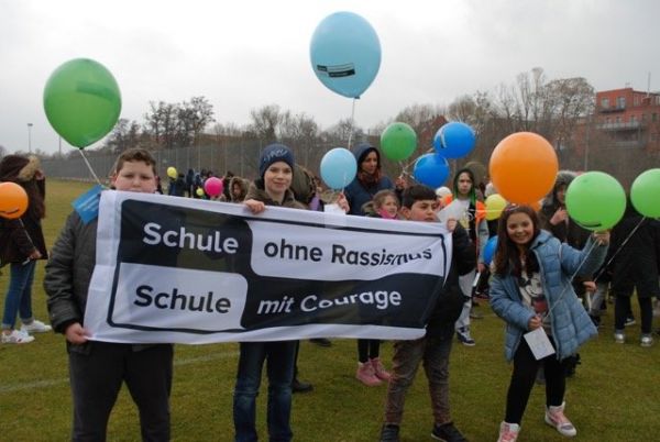 Mehrere Schüler_innen halten ein Banner von Schule ohne Rassismus