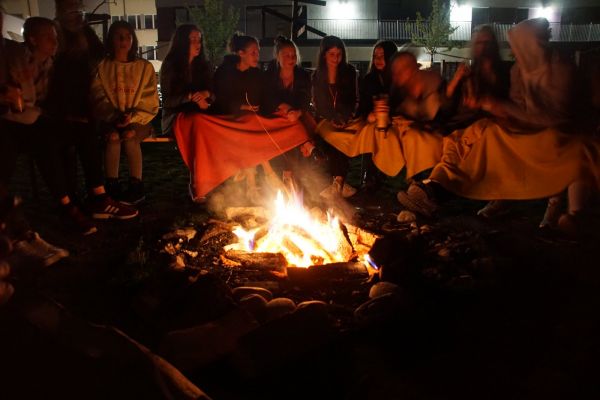 Jugendliche sitzen am Abend um ein Lagerfeuer